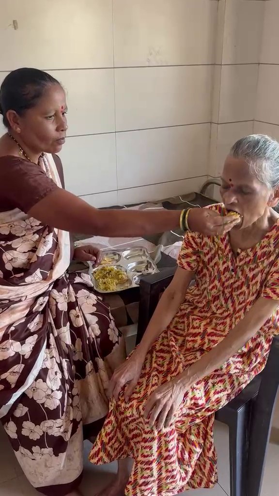 A caregiver feeding an elderly resident a midday meal