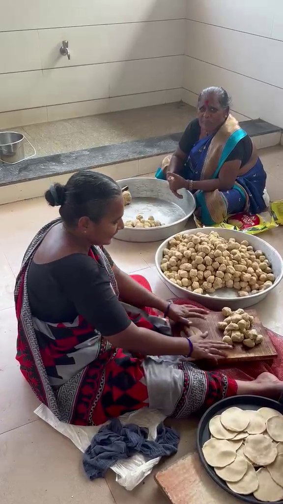 Women seated on the floor preparing food together in the kitchen