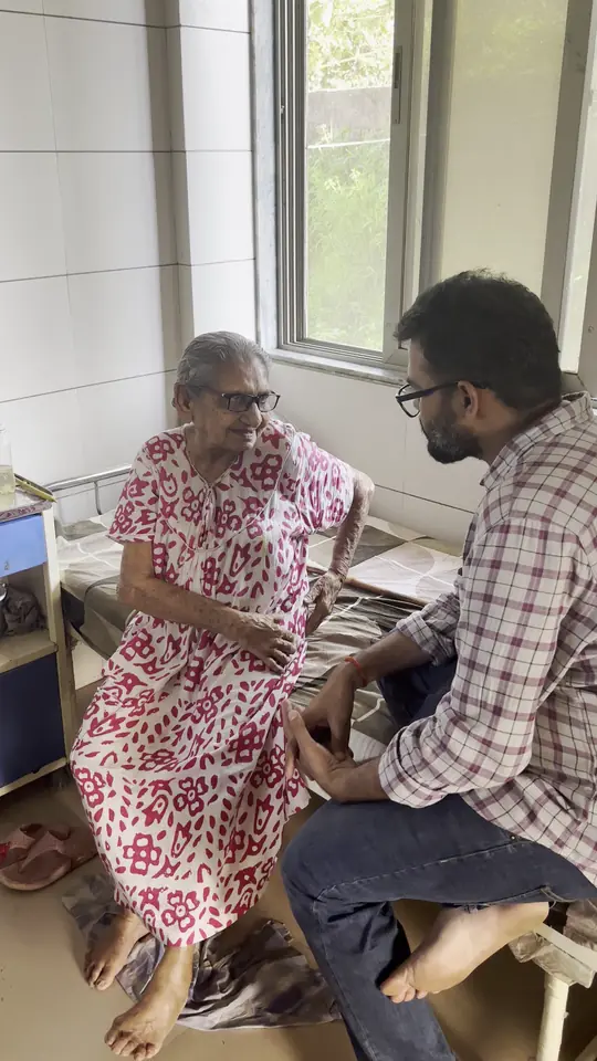 A visitor sitting and talking with an elderly woman in her room at the home