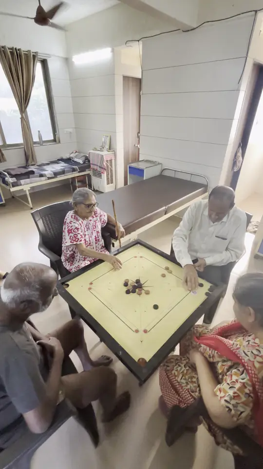 Residents gathered around a carrom board in the common room