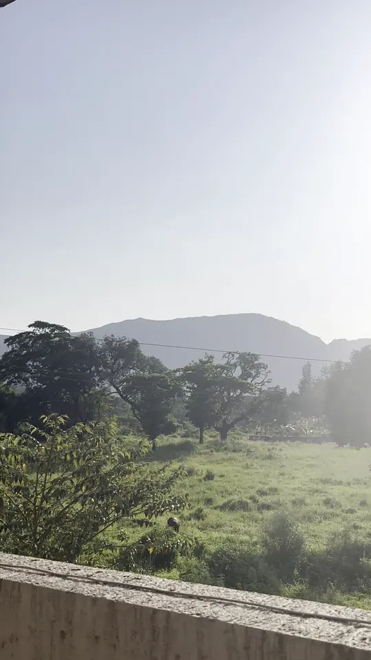 The sun low over green fields and distant hills beyond the campus